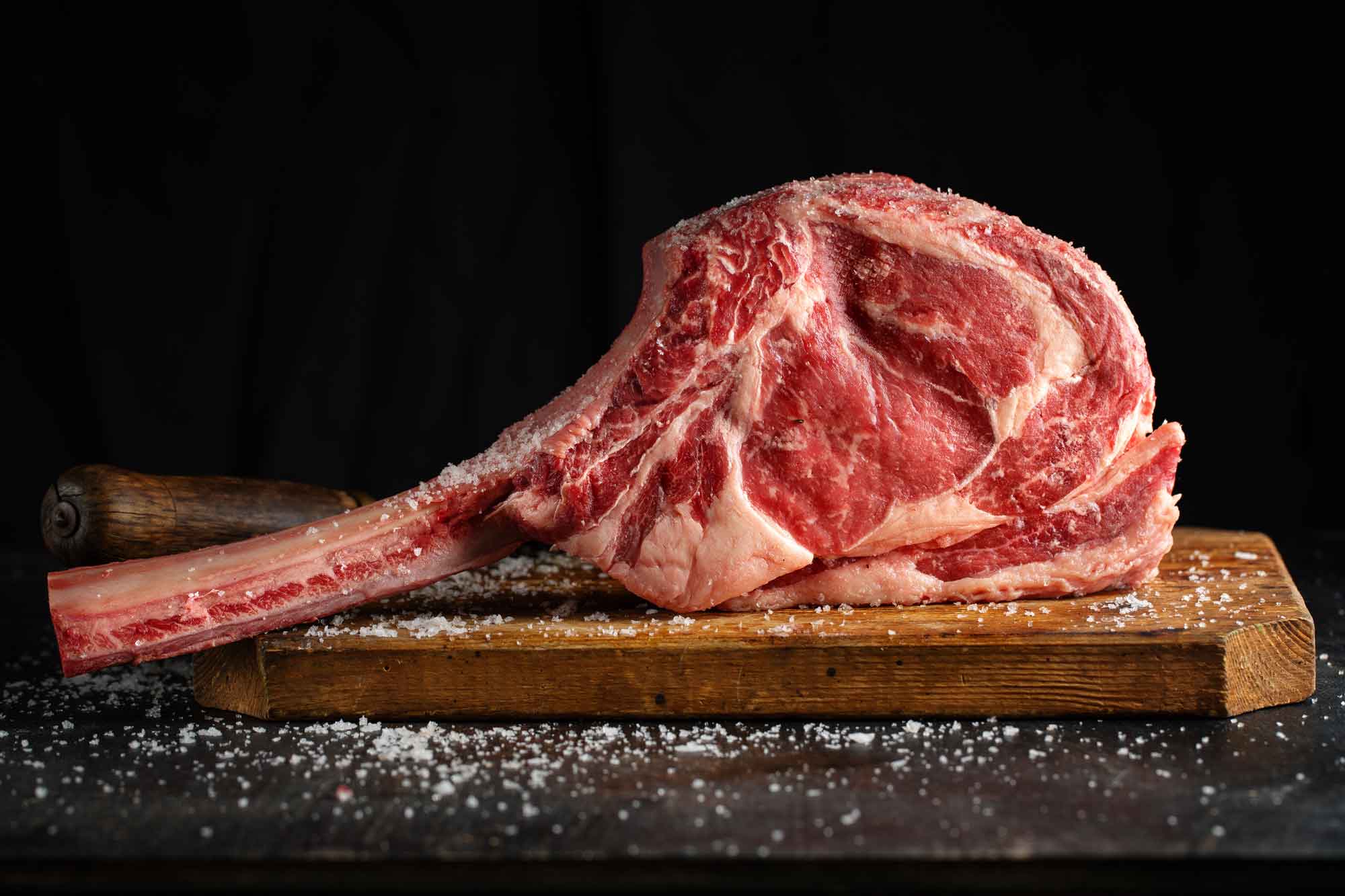 fresh-meat-tomahawk-steak-old-wooden-board-dark-background-closeup-(1)